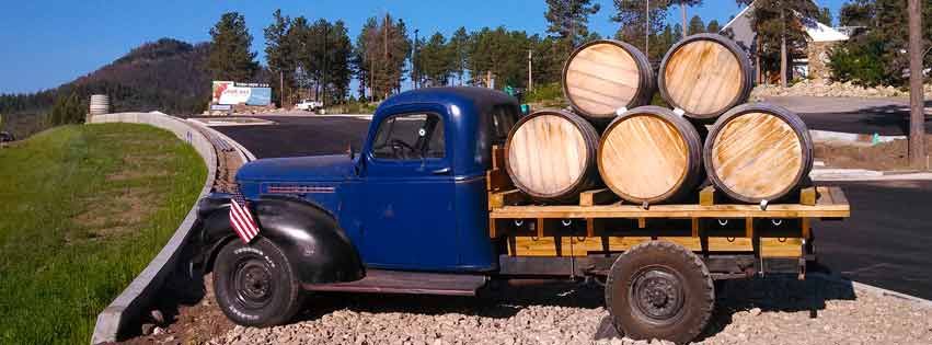old blue truck with five barrels on the back